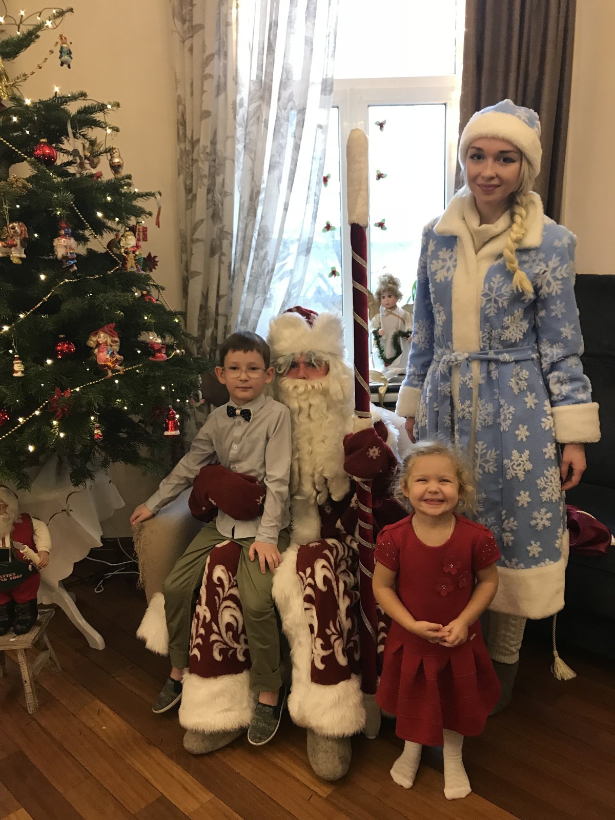 Дед Мороз с мальчиком на коленях, девочка рядом, Снегурочка у окна — визит 2018 года